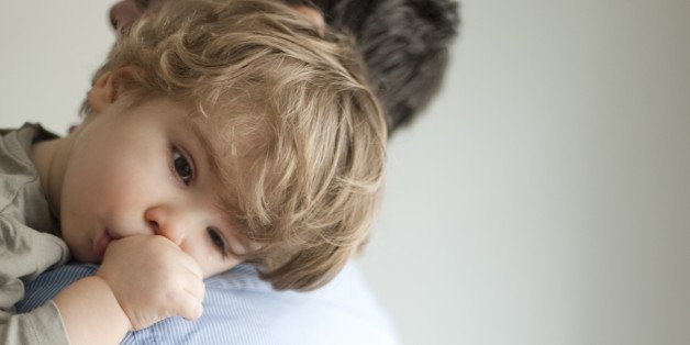 Toddler boy resting head on father's shoudler positive parenting